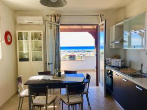 a kitchen with a dining table and a view of the ocean at Villa Sole Maldive del Salento in Torre Pali