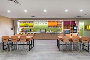 Home2 Suites By Hilton Midland East, Tx في ميدلاند: وجود كافتيريا بالطاولات والكراسي ومطبخ