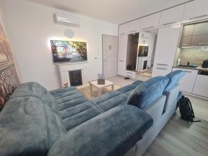 een woonkamer met een blauwe bank en een tv bij Happiness Apartman in Kecskemét