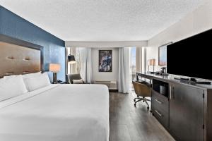 um quarto de hotel com uma cama e uma secretária com uma televisão em DoubleTree by Hilton Raleigh Midtown, NC em Raleigh