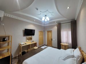 a bedroom with a large white bed and a television at Hanifa Boutique in Samarkand