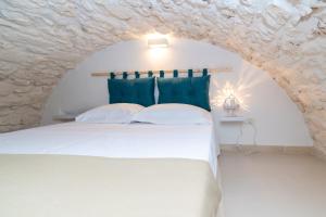 - une chambre avec un lit blanc dans un mur en pierre dans l'établissement Casa Debora, à Ostuni