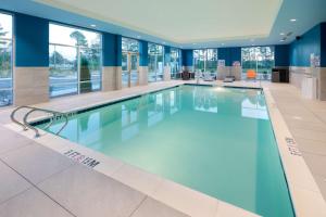 ein großer Pool in einem Gebäude mit blauen Wänden und Fenstern in der Unterkunft Hampton Inn Smithfield Selma, NC in Smithfield