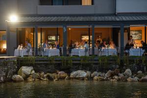a restaurant with people sitting at tables near the water at Bella Hotel & Restaurant with private dock for mooring boats in San Felice del Benaco