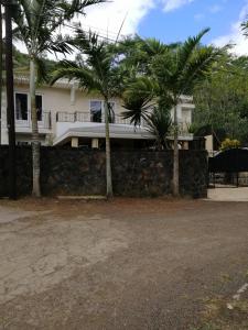 a house with palm trees in front of it at Joubarbe Residence in Moka