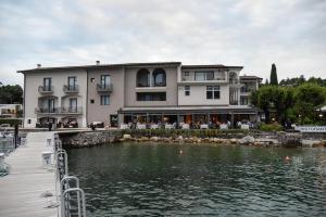 a large building next to a body of water at Bella Hotel & Restaurant with private dock for mooring boats in San Felice del Benaco