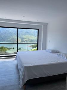 ein Schlafzimmer mit einem weißen Bett und einem großen Fenster in der Unterkunft Finca Lago Calima in Madroñal