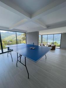eine große blaue Tischtennisplatte in einem Zimmer mit Fenstern in der Unterkunft Finca Lago Calima in Madroñal