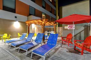 Home2 Suites by Hilton North Plano Hwy 75 في بلانو: مجموعة من الكراسي الزرقاء ومظلة حمراء