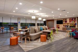 een lobby met een bank en tafels en stoelen bij Home2 Suites by Hilton North Plano Hwy 75 in Plano