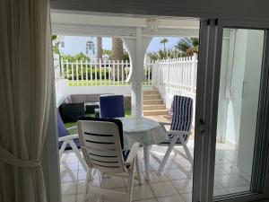 een eetkamer met een tafel en stoelen op een veranda bij Bungalow Monte Golf in Playa del Inglés