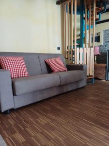 un sofá gris con 2 almohadas rojas en la sala de estar en CASA VACANZE CA' MORESCHI, en Berzo