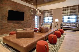 Homewood Suites by Hilton Tuscaloosa Downtown, AL في توسكالوسا: غرفة معيشة مع أريكة وكراسي وتلفزيون