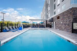 Hampton Inn & Suites North Port, Fl في نورث بورت: مسبح وكراسي زرقاء ومبنى