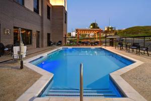 une grande piscine bleue avec des tables et des chaises dans l'établissement Homewood Suites by Hilton Tuscaloosa Downtown, AL, à Tuscaloosa