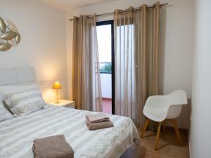 a bedroom with a bed and a chair and a window at Casa Mimi - your perfect family getaway in Corralejo