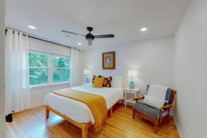 een slaapkamer met een bed, een stoel en een raam bij Razorback Retreat in Fayetteville