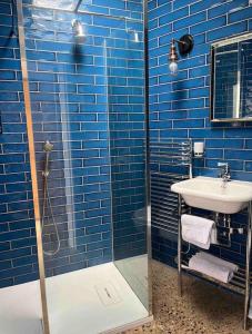een blauwe betegelde badkamer met een wastafel en een douche bij Stunning Barn, Bowes, Barnard Castle in Barnard Castle