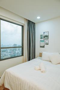 a bedroom with a white bed with a large window at Louisa The Gold View Apartment in Ho Chi Minh City
