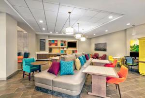 un soggiorno con divano, tavoli e sedie di Home2 Suites by Hilton Minneapolis Downtown a Minneapolis