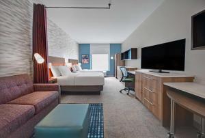 Hotelzimmer mit Sofa und TV in der Unterkunft Home2 Suites By Hilton Raleigh North I-540 in Raleigh