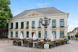 un gran edificio blanco con sombrillas delante en Villa Fokken Steuermannsquartier, en Esens
