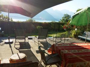 une terrasse avec une table, des chaises et un parasol dans l'établissement Maison à 30 mètres du lac et piste cyclable, à Sévrier