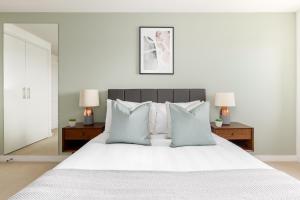 um quarto com uma cama branca e almofadas azuis em The Wimbledon Collection em Londres