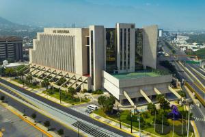 un grande edificio con un campo da tennis di fronte ad esso di MS Milenium Monterrey Curio Collection by Hilton a Monterrey