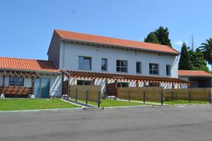 ein weißes Haus mit einem Zaun davor in der Unterkunft El Molino 2 in Muros de Nalón