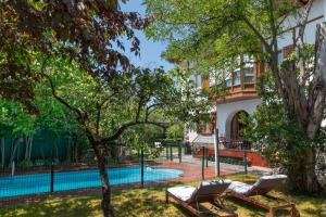 Villa Ganbara, 5 minutos de Pamplona في فييافا: مسبح في الحديقة الخلفية لبيت فيه كرسيين جلوس واشجار