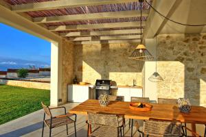 an outdoor kitchen with a wooden table and chairs at Villa Acropolitana by PosarelliVillas in Acharavi