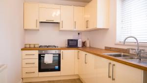 a kitchen with white cabinets and a sink at JOIVY Charming 3-bed house in Walsall in Bescot