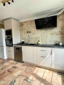 a kitchen with white cabinets and a black counter top at Villa Martha - Appt 01 in Guéthary