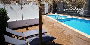 a swimming pool with a table and a chair next to it at Burgau Charming House Loft in Burgau