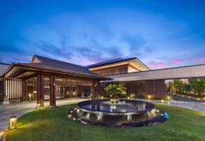 a house with a fountain in the middle of a yard at Hilton Shanghai Songjiang Guangfulin in Songjiang