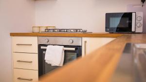 a kitchen with a stove and a microwave at ALTIDO Charming 3-bed house in Walsall in Bescot