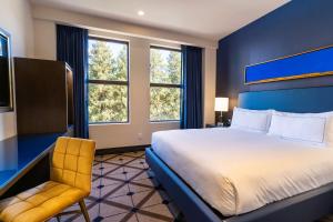 a bedroom with a large bed and a chair at The Exchange Sacramento, Curio Collection By Hilton in Sacramento
