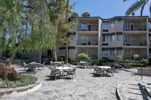 un patio con mesas y sillas frente a un edificio en The Belamar Hotel Manhattan Beach, Tapestry by Hilton, en Manhattan Beach