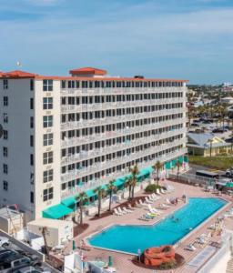 a large hotel with a large swimming pool and chairs at Oceanfront Oasis in Daytona Beach