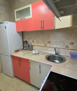 a kitchen with red cabinets and a sink and a refrigerator at Майлина 10 аэропорт in Turksib