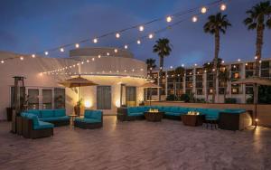 a hotel patio with blue furniture and palm trees at night at Redondo Beach Hotel, Tapestry Collection by Hilton in Redondo Beach