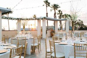una recepción de bodas en la playa con mesas y sillas blancas en Redondo Beach Hotel, Tapestry Collection by Hilton en Redondo Beach