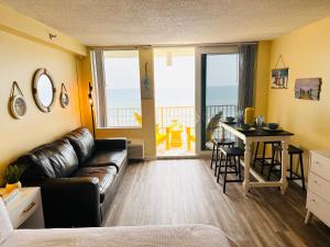 a living room with a leather couch and a table with a view at Oceanfront Oasis in Daytona Beach