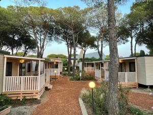 uma fila de casas móveis com árvores ao fundo em Camping I Melograni em Marina di Bibbona