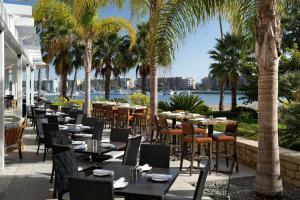 een restaurant met tafels en stoelen en palmbomen bij Jamaica Bay Inn Marina Del Rey Tapestry Collection by Hilton in Los Angeles