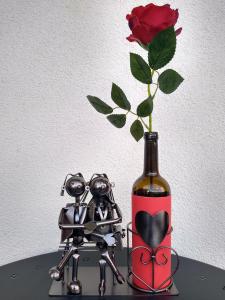 a vase with a flower and two metal robots next to a bottle at Sunrise Apartment in Madona