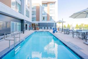 una piscina con tavoli e sedie e un edificio di Homewood Suites By Hilton Sunnyvale-Silicon Valley, Ca a Sunnyvale