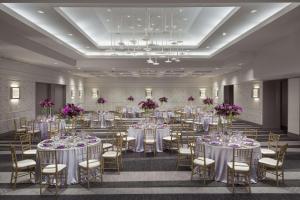 un salón de banquetes con mesas y sillas blancas y flores púrpuras en Hilton Washington DC Capitol Hill, en Washington