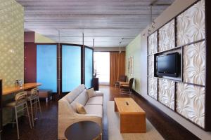 ein Wohnzimmer mit einem Sofa und einem TV an der Wand in der Unterkunft Tulyp, Tapestry Collection by Hilton in Holland